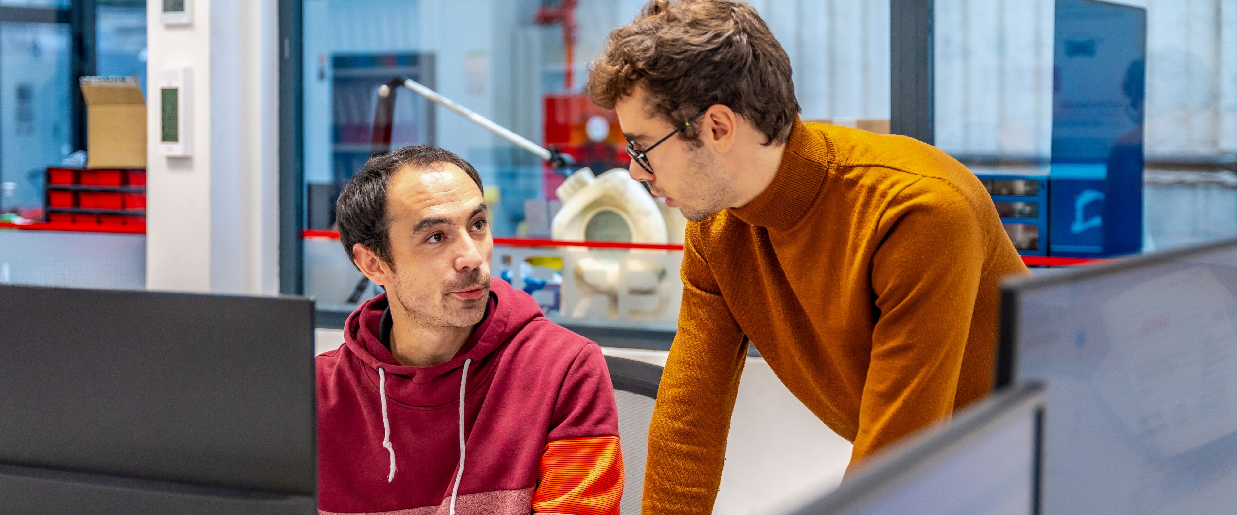 Two engineers analyze their project at a workstation
