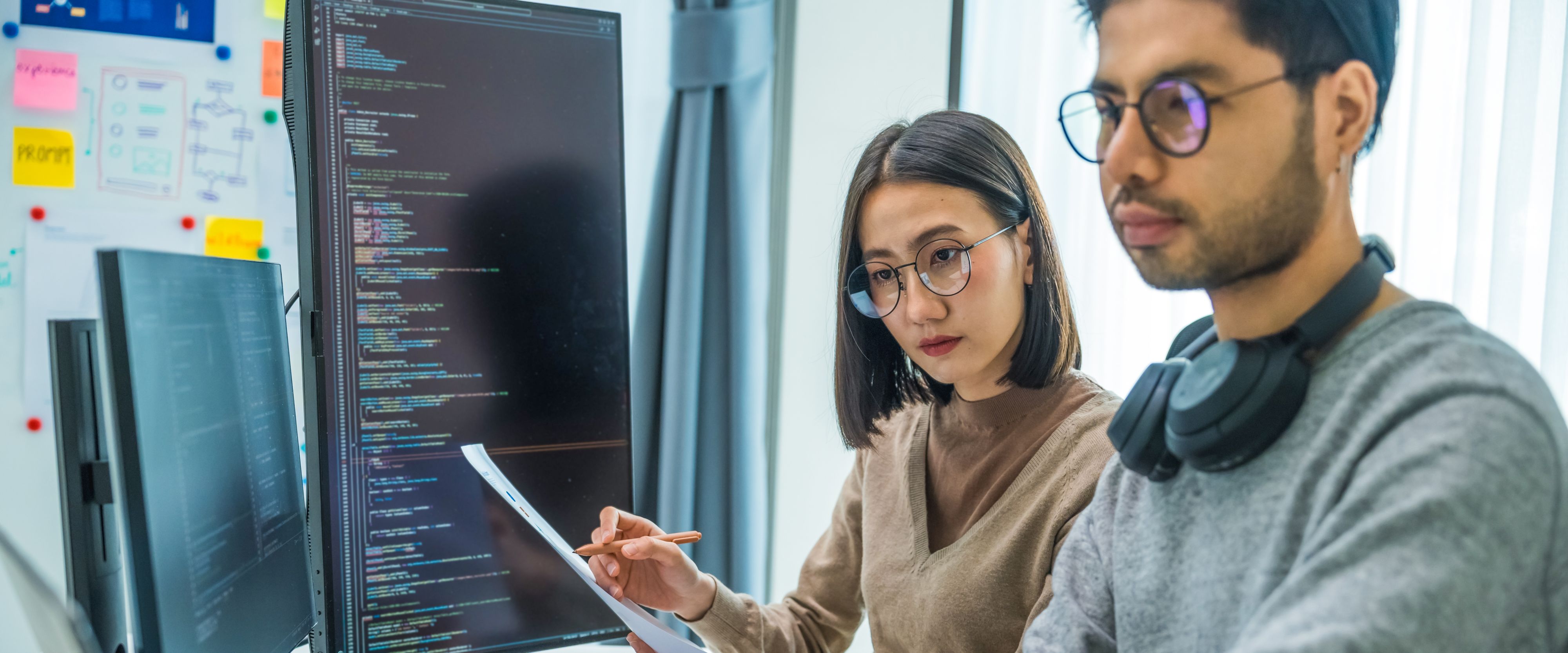 Two computer programmers evaluate lines of code together