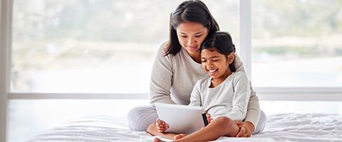 Woman holding child on her lap viewing content on a laptop