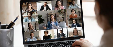 An open laptop with thirteen people on screen during a video call  