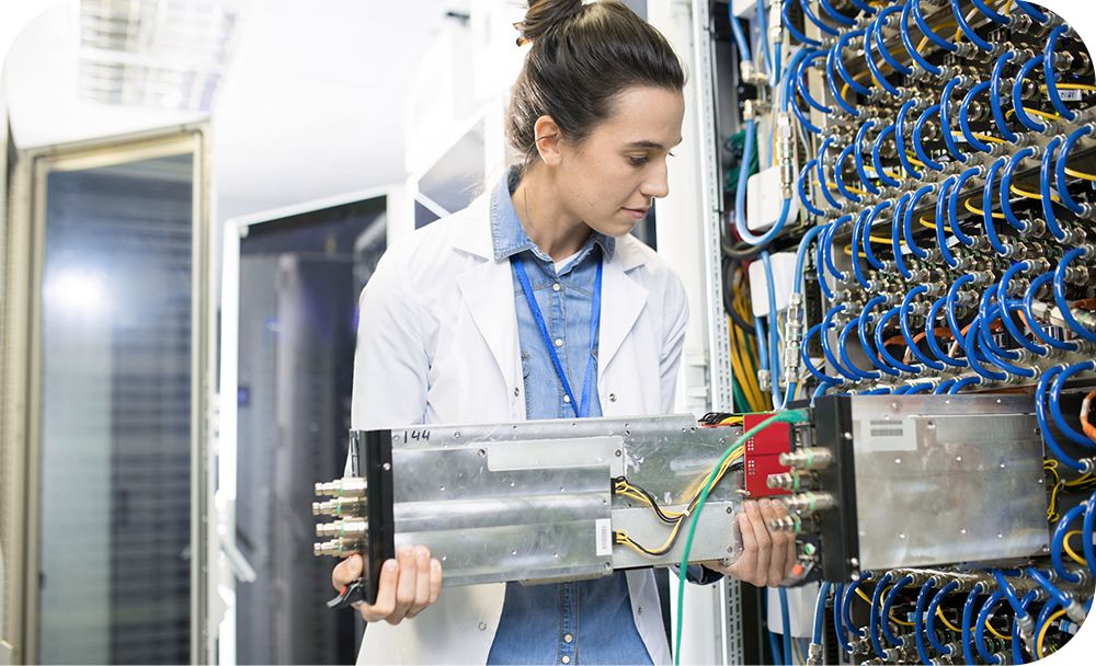 An IT professional in a white blazer changes out equipment in a server room 