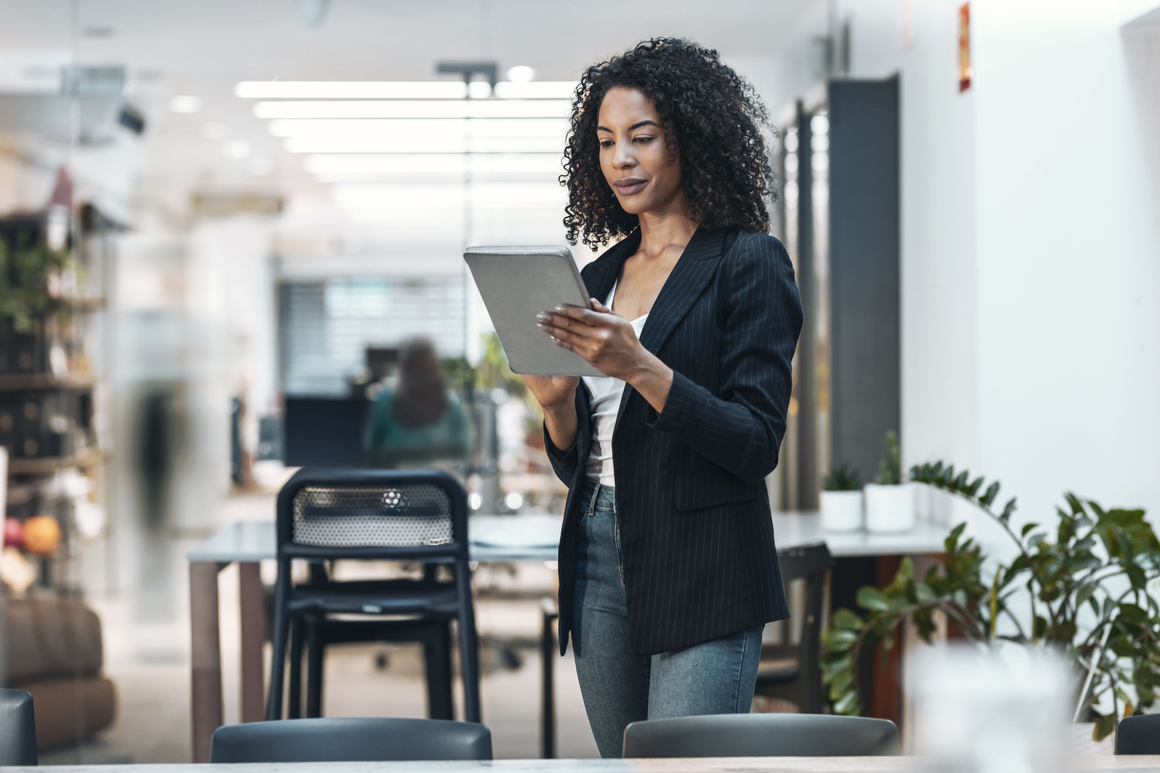 A professional holds a tablet in an office environment. 