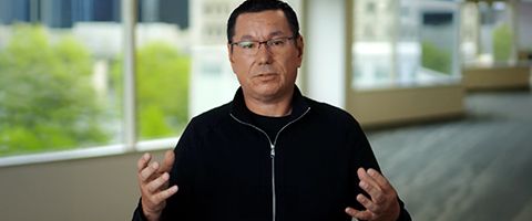 Scott Yow in a dark jacket stands in a room of windows.