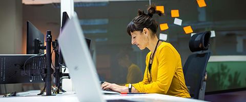 A businessperson typing on a computer in an office. 