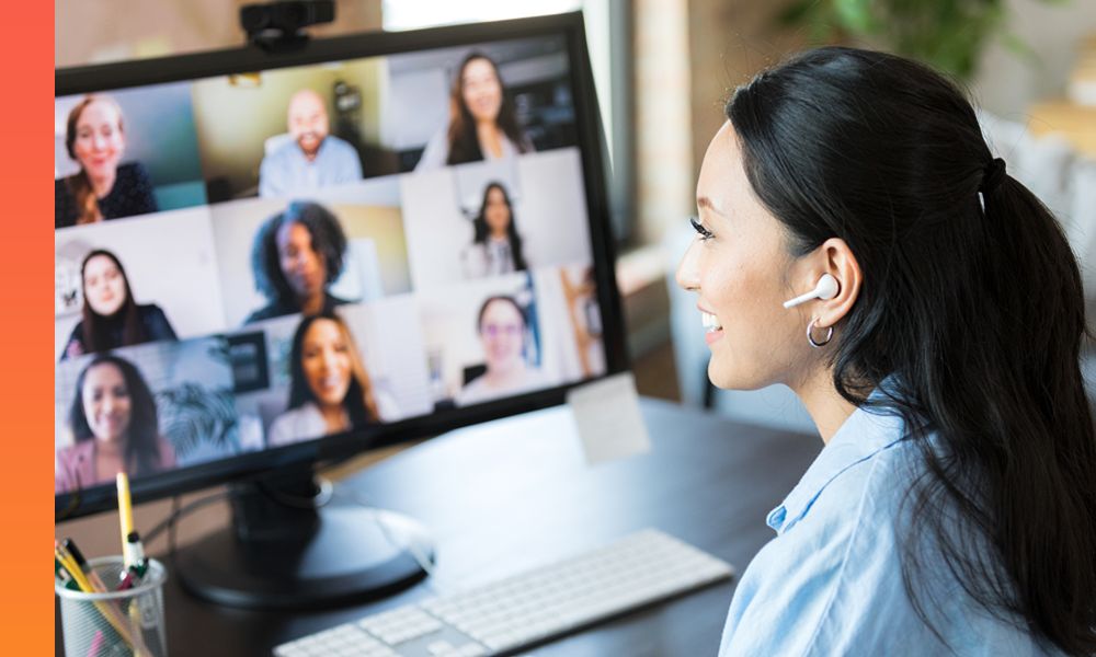 Woman sitting at a desk with headphones on while on a video conference with nine other people