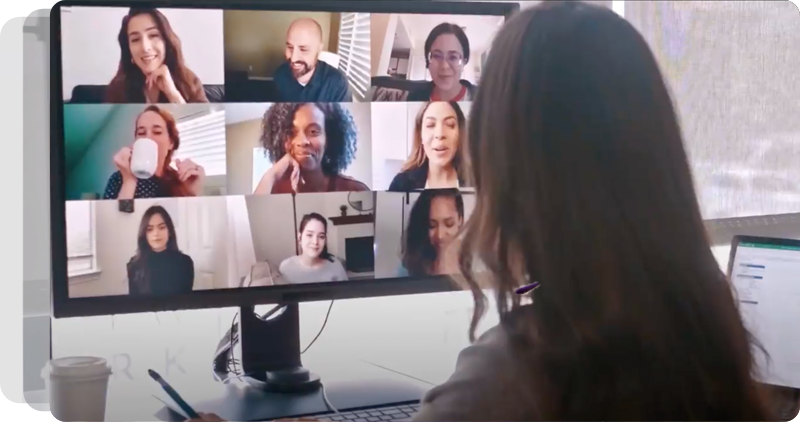 An employee looks at a computer screen showing a 3-by-3 grid of participants on a video call