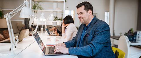 A person works on a laptop in a bright office.