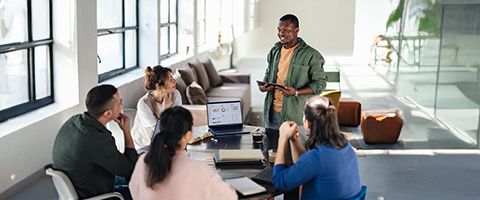 A person gives a presentation to a small group in a bright office.