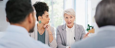 A group of people talk in front of a window.