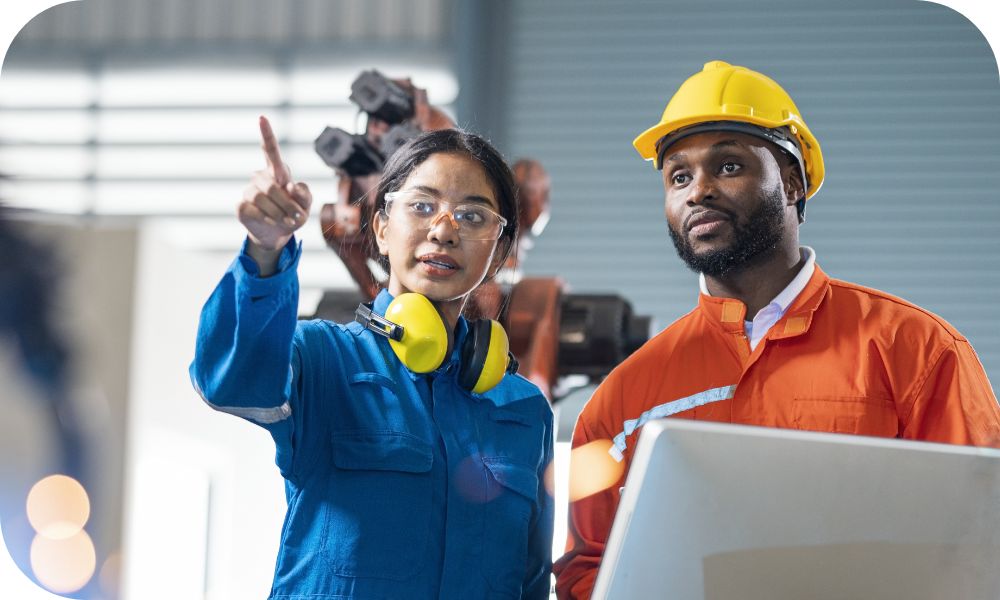 Two workers in protective gear standing together and looking at something in front of them 