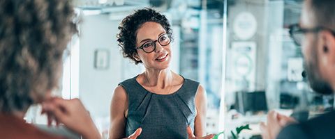 A person in glasses talks to two other people in a lab.