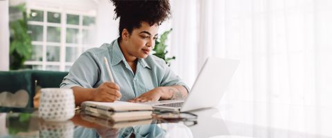 Presenter with a laptop looking at a monitor in a meeting with an audience. 