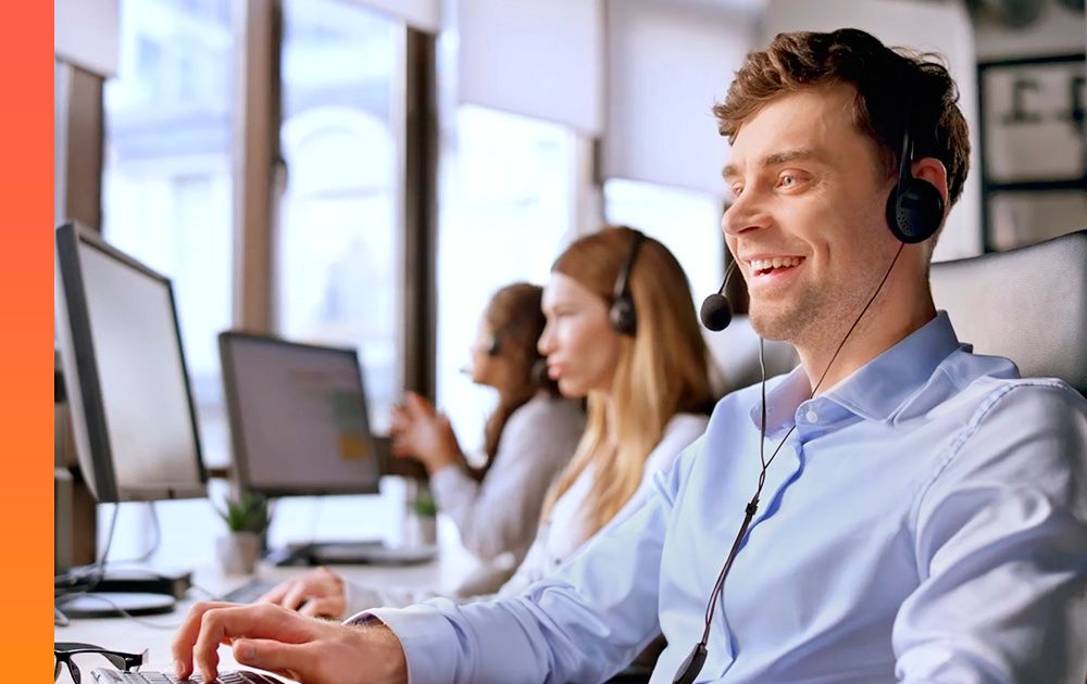  Row of customer support technicians with headsets reviewing data on computer screens at their desk. 