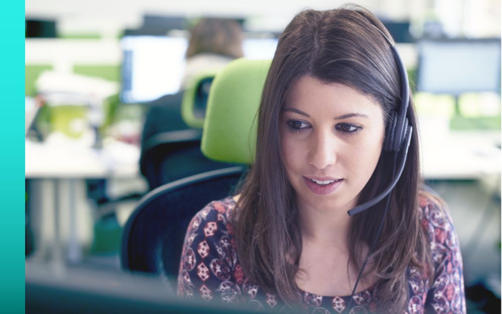 A customer service representative talks on a headset in a bright room