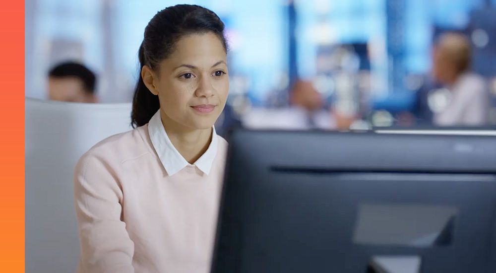 A woman works on a desktop computer in an office