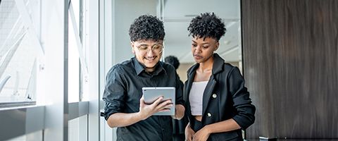 Two people in black shirts standing while looking at a tablet device