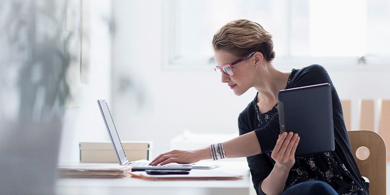 Weibliche Fachkraft, die an einem Desktop arbeitet und auf einen Monitor schaut, auf dem Datenmetriken angezeigt werden.
