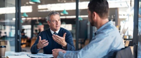 Two men have a discussion in an office area