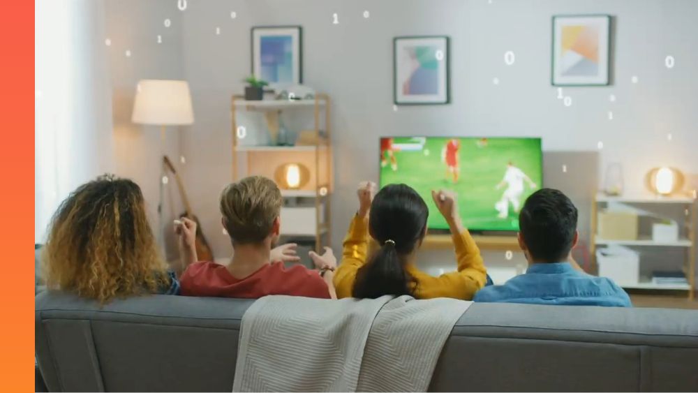 Four people sitting on a couch together watching a soccer game on a flatscreen TV