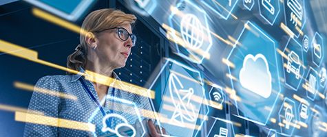 Female technology professional viewing a large display with network and cloud icons.