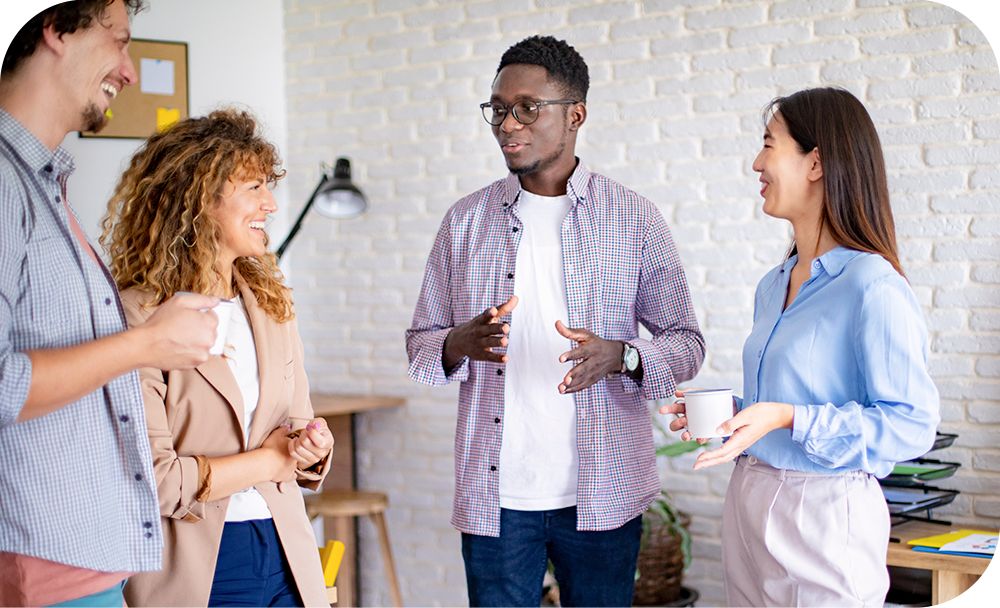 Man standing in the middle of three other people while the group talks and laughs