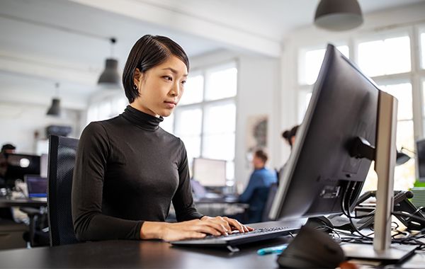 Geschäftsfrau, die an einem Schreibtisch sitzt, während sie an einem Computer arbeitet