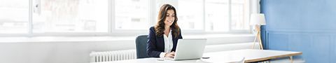 A person in business attire works on a laptop at a table