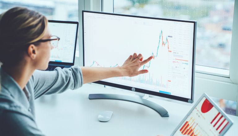 Empresaria mirando un gráfico dentro de una plataforma de informes en un monitor de computadora