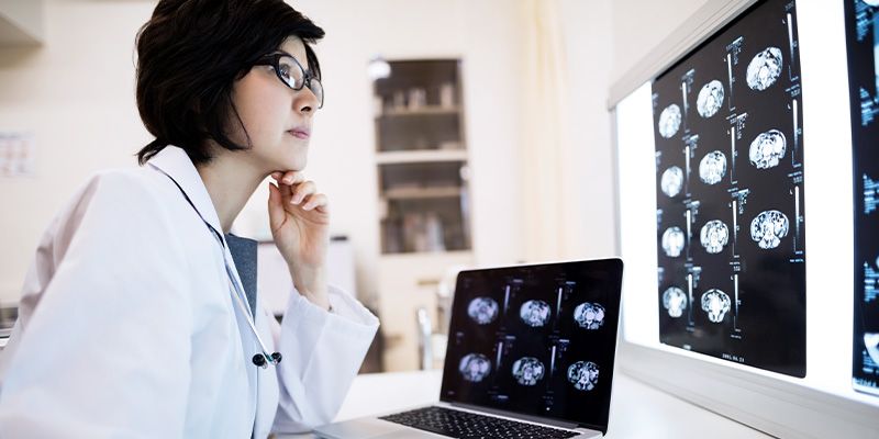 Doctor sitting at a desk in front of a laptop open to the same x-rays she is looking at on the wall