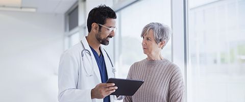 A doctor holding a tablet discusses medical information with a patient 