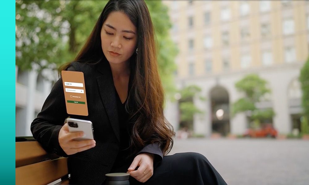  Woman in a dark grey suit sitting down while looking down at her phone with a graphic of her screen over it