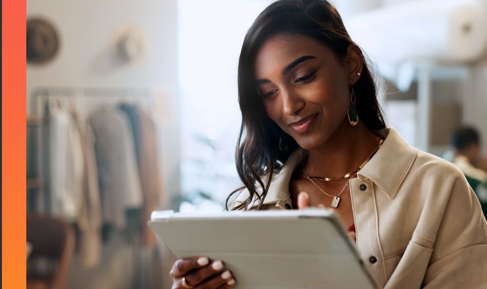 A person in a brightly lit retail store smiles and uses a tablet