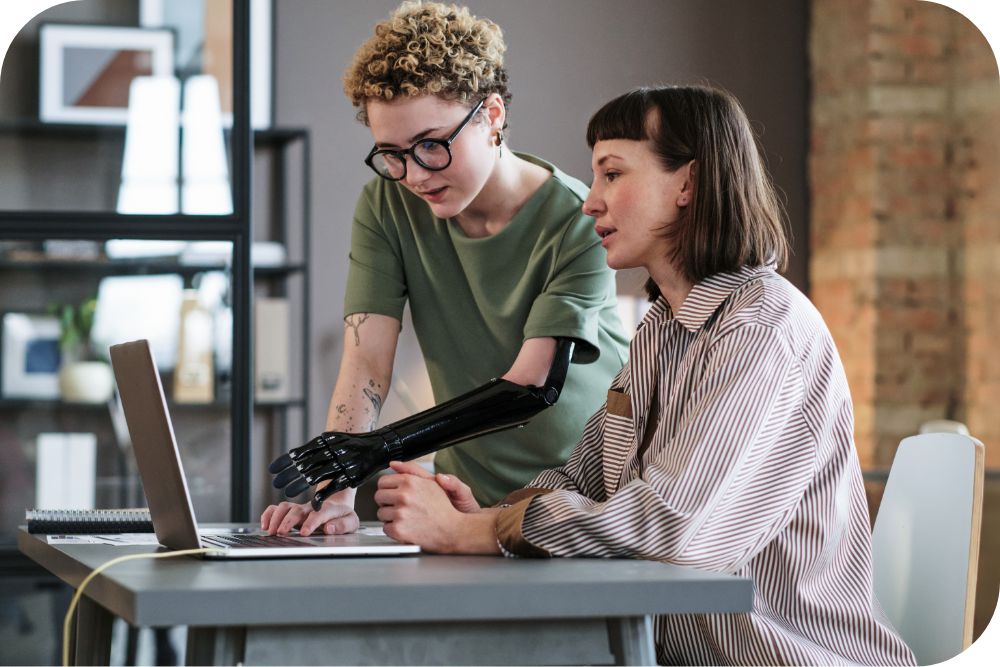 Two people work on a laptop at a table.