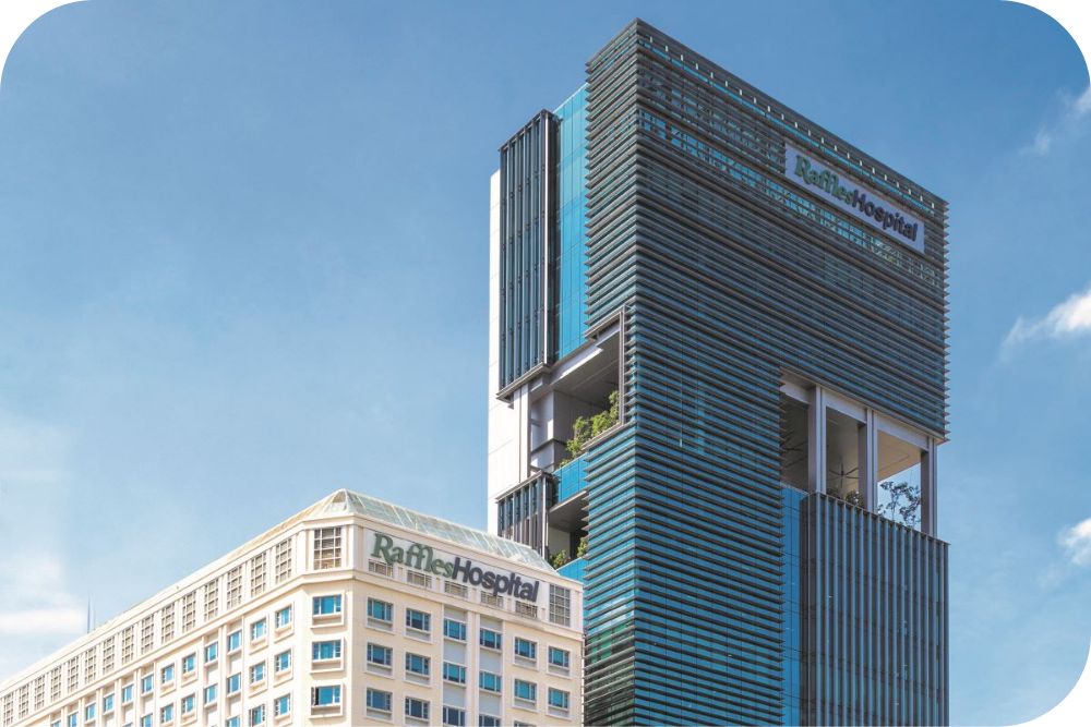 The RafflesHospital buildings stand tall against a clear blue sky.  