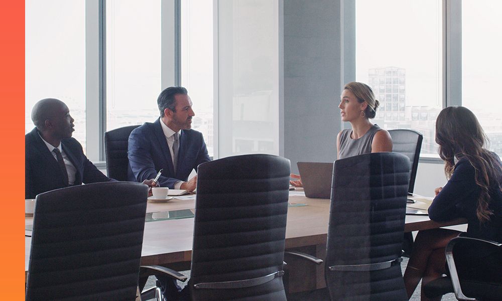 Diverse group of professionals in a modern boardroom discussing business.