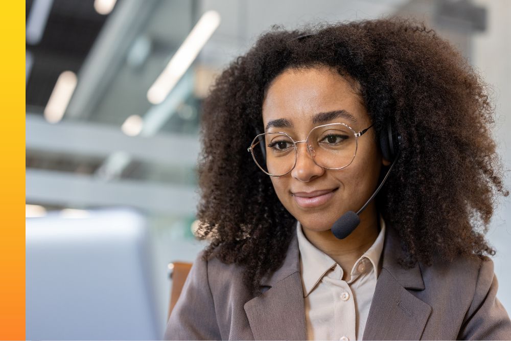 Businessperson smiles at their laptop while wearing a headset.