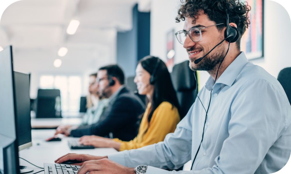 Businessperson works on computer while wearing a headset. 