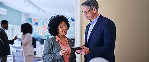 Two people in an office look at a tablet.