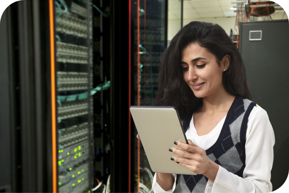 An individual in a data center smiles while working on a tablet.