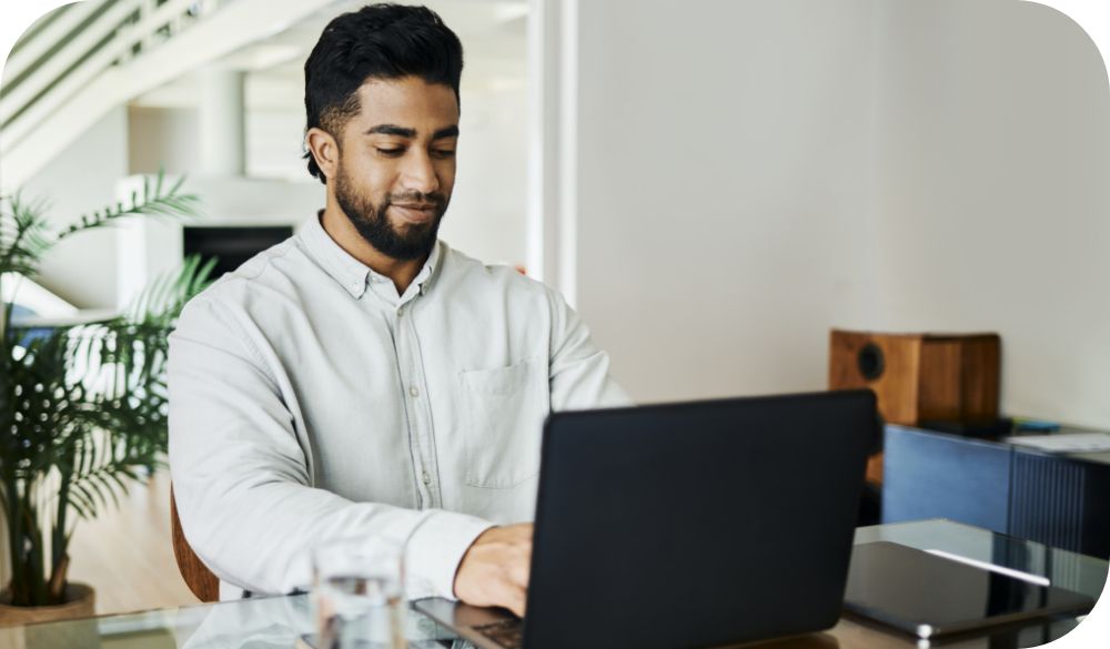 Businessperson works on laptop at home desk.