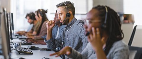 A customer service representative sits in a row with others and works.