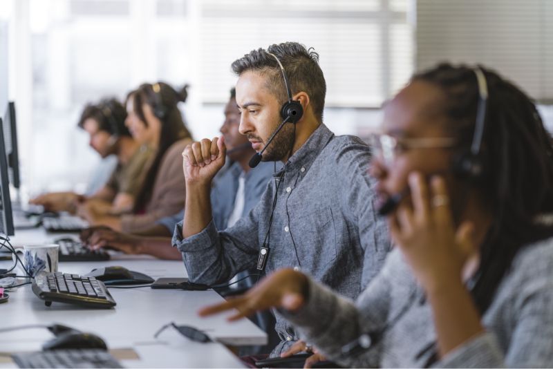 Call center employees talk on headsets in front of computers