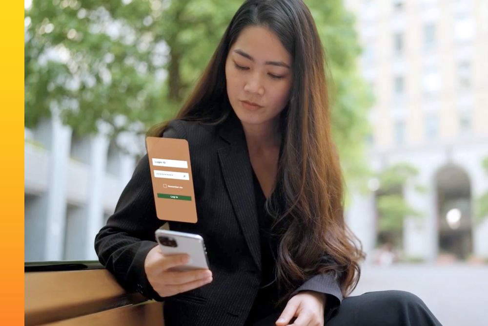 Woman in a dark grey suit sitting down while looking down at her phone with a graphic of  her screen over it