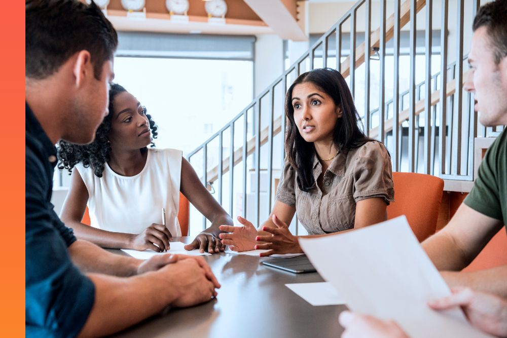 Four people sitting around a conference table while working and talking