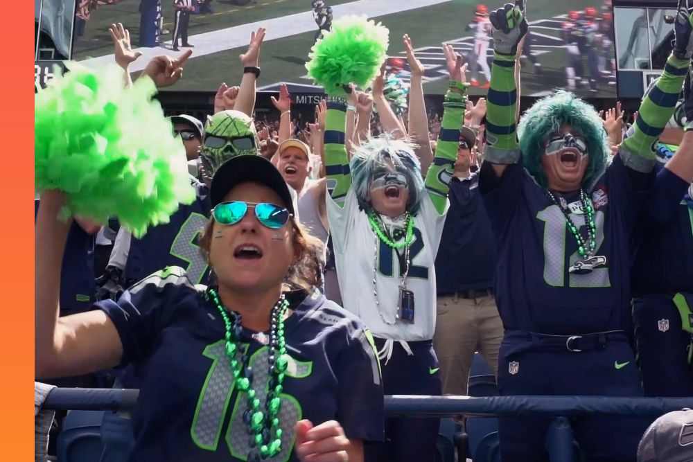 A group of fans at a sports event, dressed in team gear with their arms raised and waving pom-poms