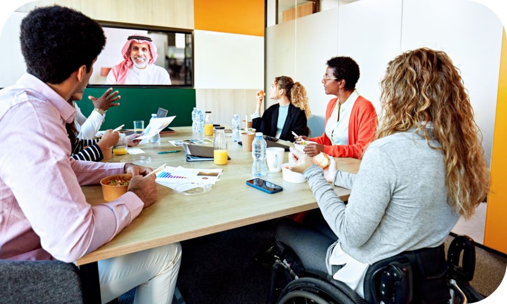 A group of people sitting at a conference table while on a video call