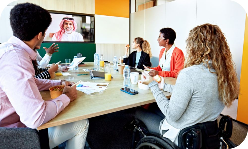 A group of people sitting at a conference table while on a video call