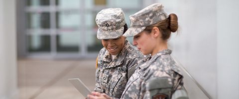 Two government employees in camouflage uniforms look at a tablet screen