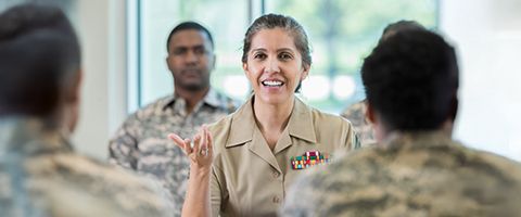 A leader gives a talk to a group of people, all dressed in military uniforms 