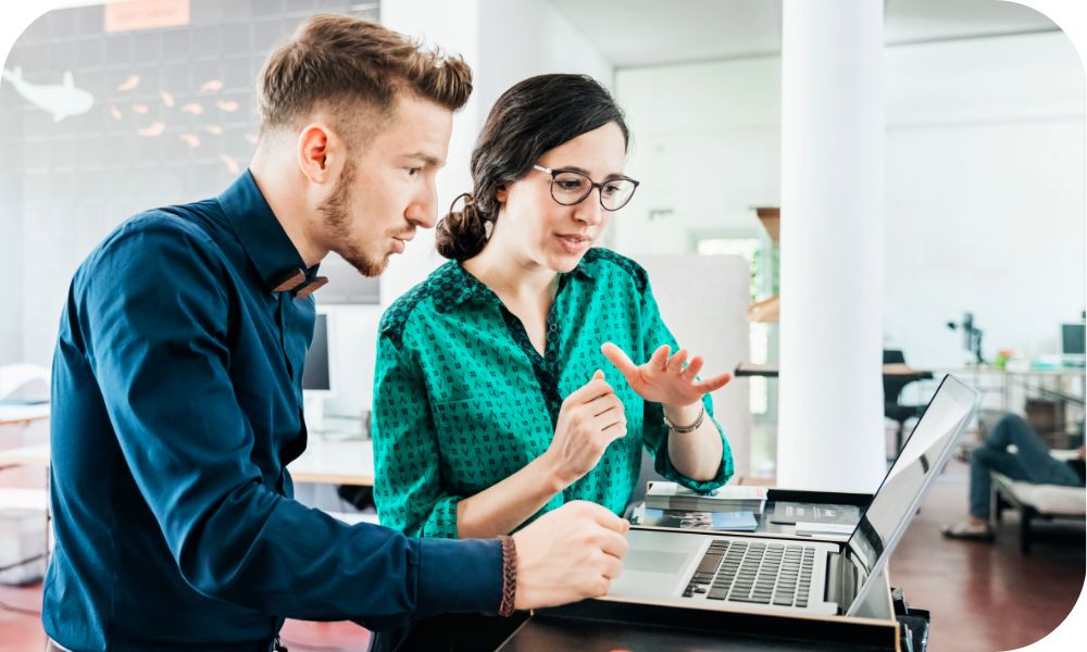 Two business colleague looking intently while discussing data on the laptop in front of them.  